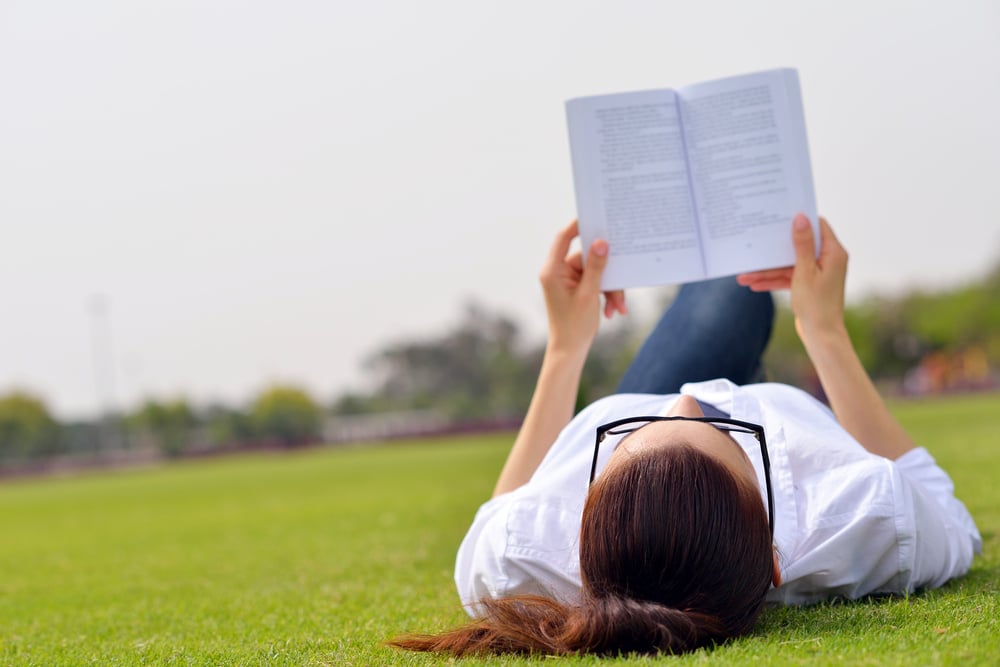 Young student woman reading a book and study in the park